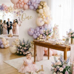 One year old girl in a butterfly-inspired outfit beside a soft and elegant first birthday party setup