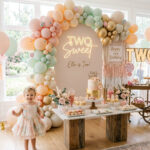 Two year old in a Two Sweet birthday outfit beside a stylish second birthday setup
